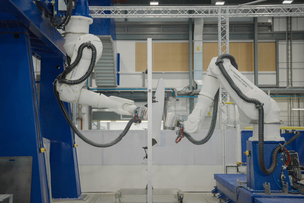 Two robotic arms x-raying a sheet of metal